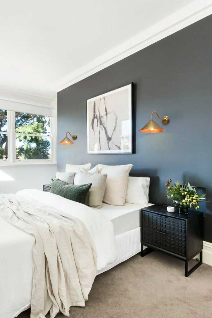 Two brass wall lights in bedroom above the bed