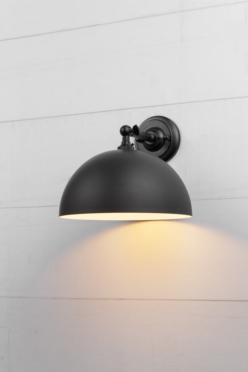 Small black dome shade on a steel black straight arm wall sconce