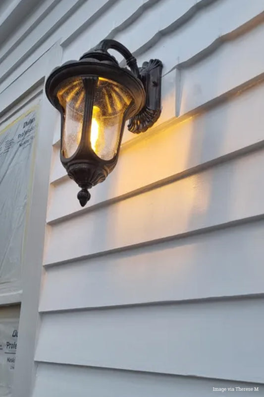 Traditional outdoor wall lantern in black on a white weather board house. 