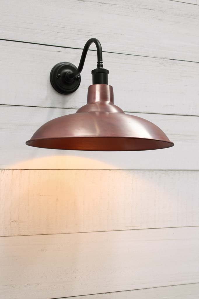 Solid copper bullpit shade on a black gooseneck wall sconce.