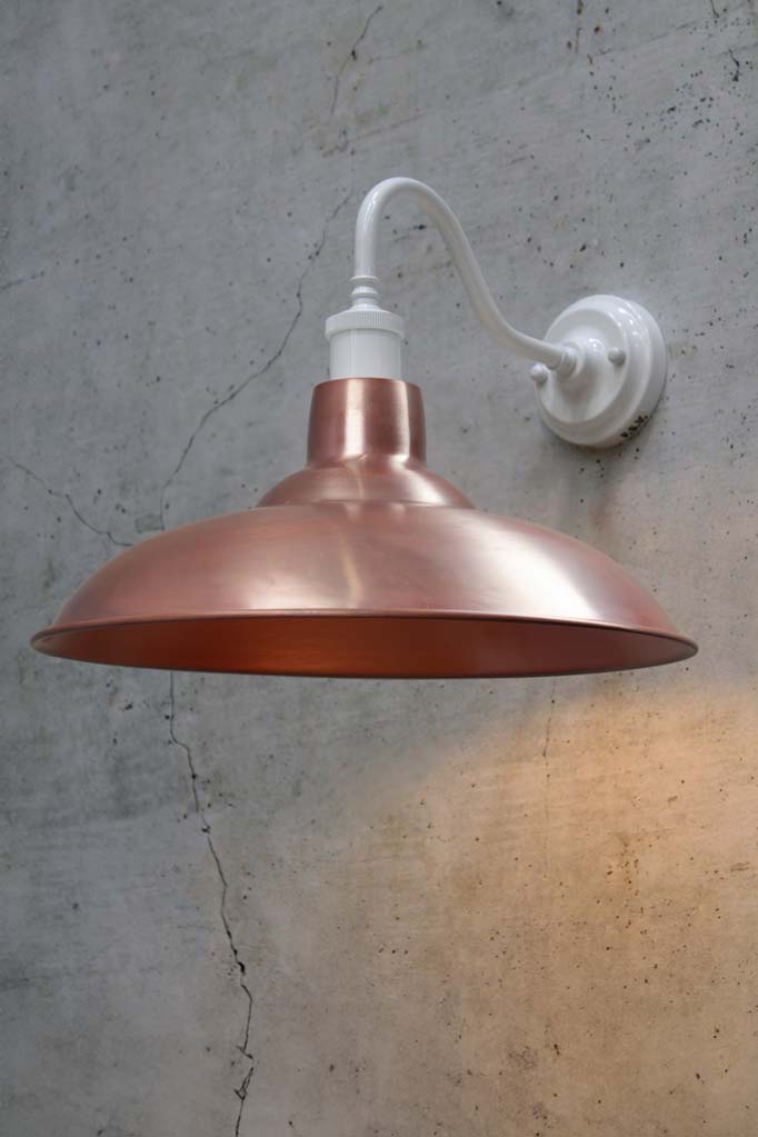 Solid copper bullpit shade on a white gooseneck wall sconce.