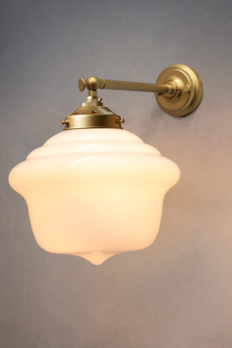 Schoolhouse shade on a gold/brass straight arm wall sconce