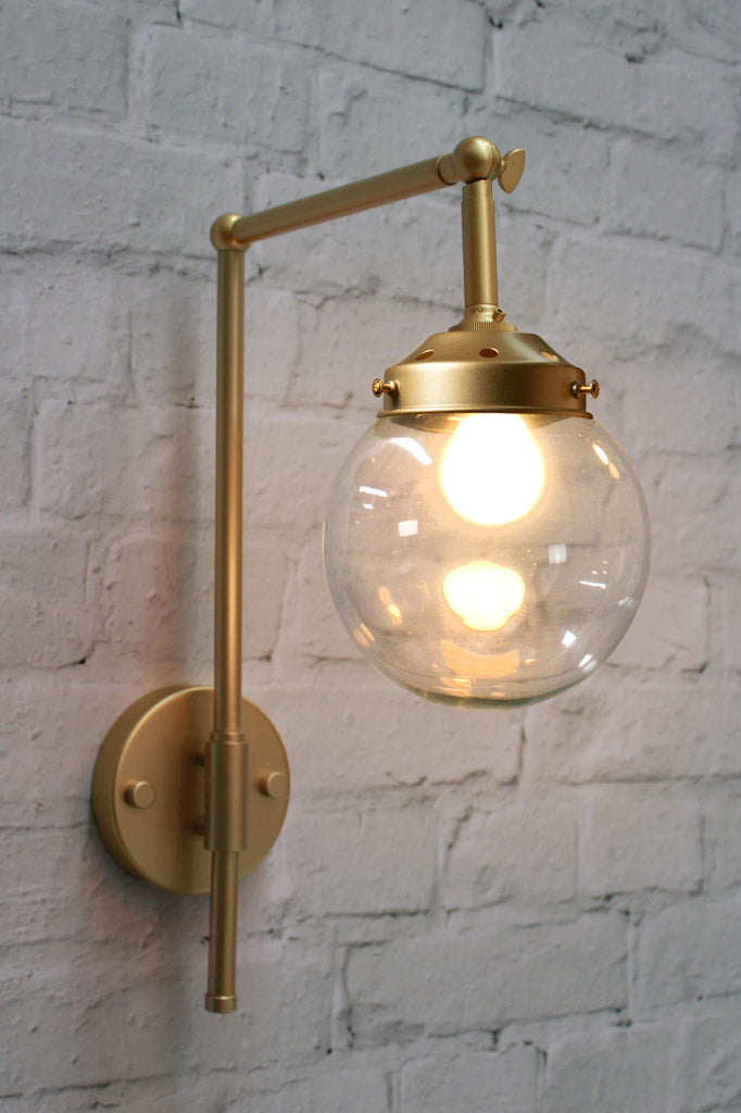 Small clear galss ball shade on the gold/bass hook wall sconce. 