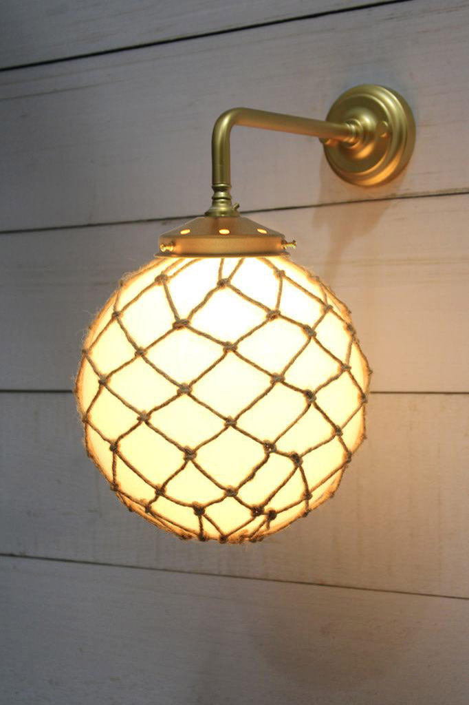 Medium, opal glass ball shade with rope detail on a 90 degree arm wall sconce in gold/brass. 