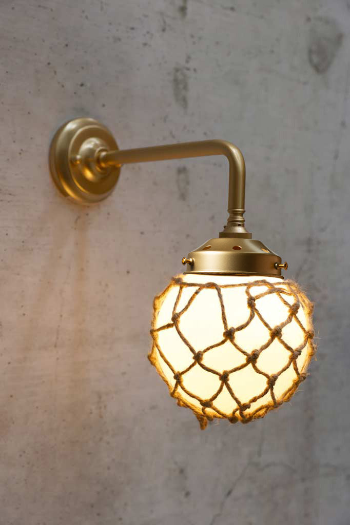 Small, opal glass ball shade with rope detail on a 90 degree arm wall sconce in gold/brass. 