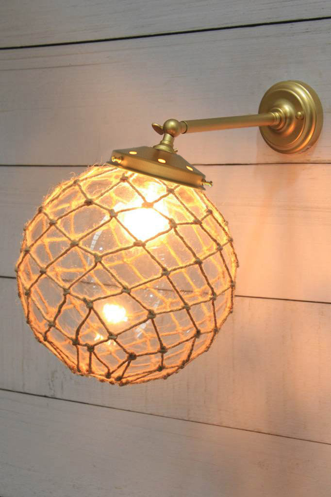 Medium, clear glass ball shade with rope detail on a long straight wall sconce in gold/brass. 