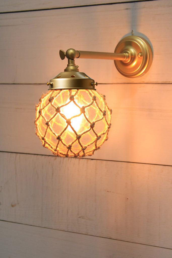 Small, clear glass ball shade with rope detail on a long straight wall sconce in gold/brass. 