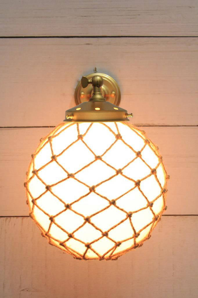 Medium, opal glass ball shade with rope detail on a long straight wall sconce in gold/brass. 