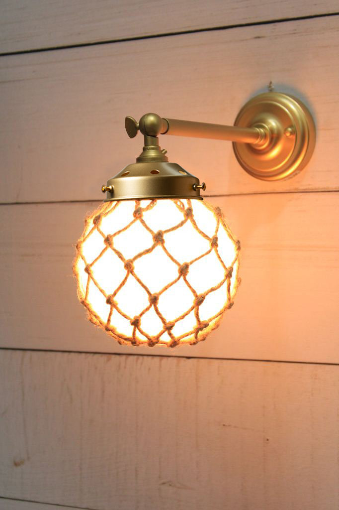 Small, opal glass ball shade with rope detail on a long straight wall sconce in gold/brass. 