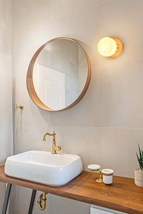 glass  ball wall light with gold brass disc in a bathroom 