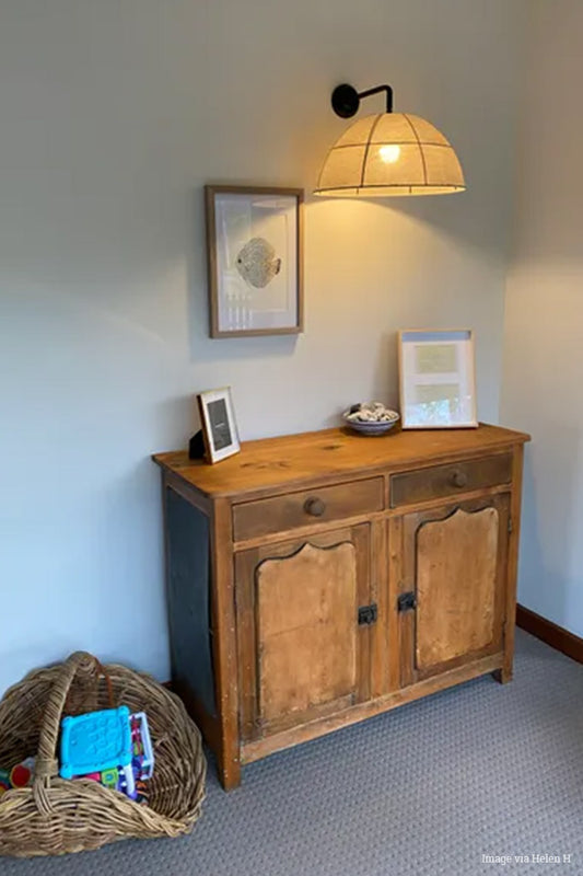 Large linen shade on a black wall arm hanging over a side board. 