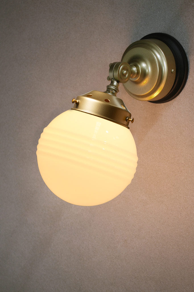 Ridged opal glass ball shade on a gold/brass wall sconce