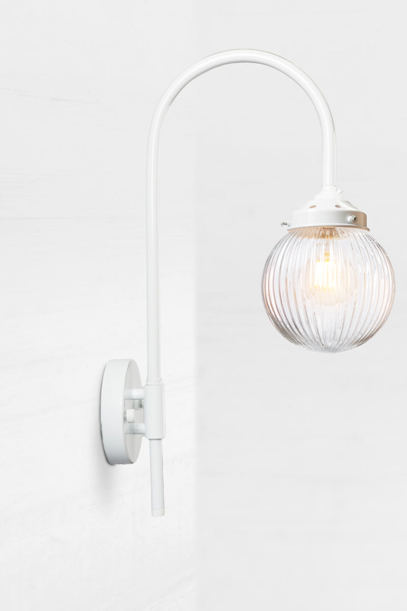 Shepard gooseneck wall light in white with a clear reeded glass ball shade. 