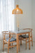 Wooden pendant light with a white cord hanging over a a dining area.