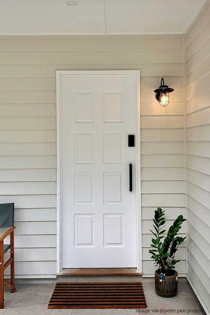 A black Strandhill Outdoor Light installed on a cream and white home's front entrance. 