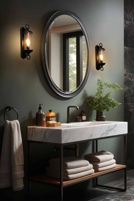 Two Gladestry Exterior Wall Light's used as vanity lighting, shown either side of a large round mirror in a moody bathroom.