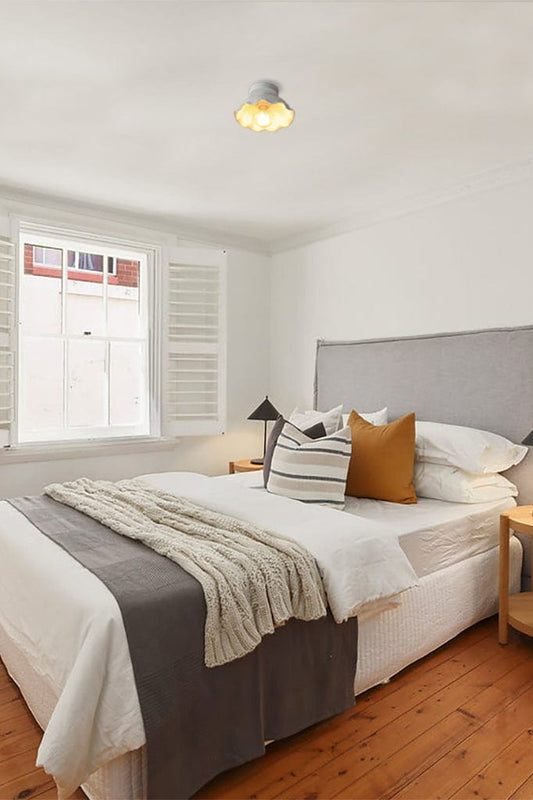 Flush mount ceiling light with ceramic shade and black ceiling rose in a bedroom setting