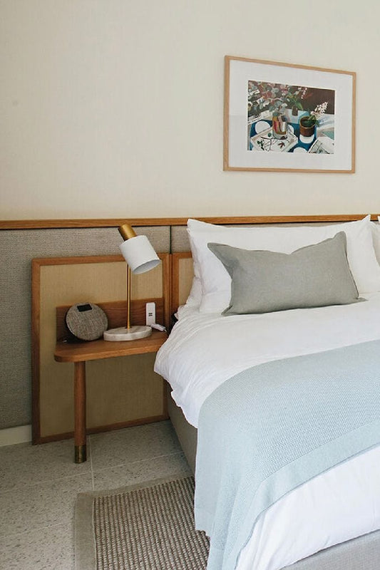 White and brass table lamp with a marble base on a bedside table