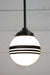 Hand painted opal glass ball pendant light with three stripes hung from black steel pole. 