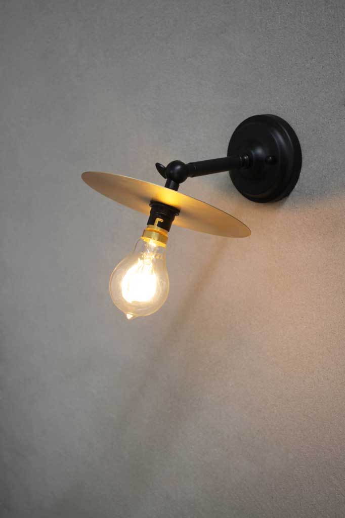 Short black adjustable sconce with brass disc