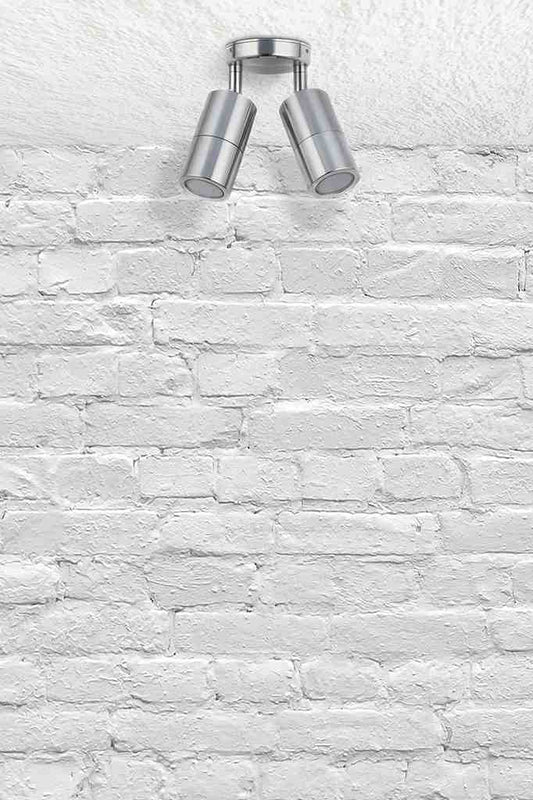 Twinlight spotlight in titanium affixed on a brick wall.