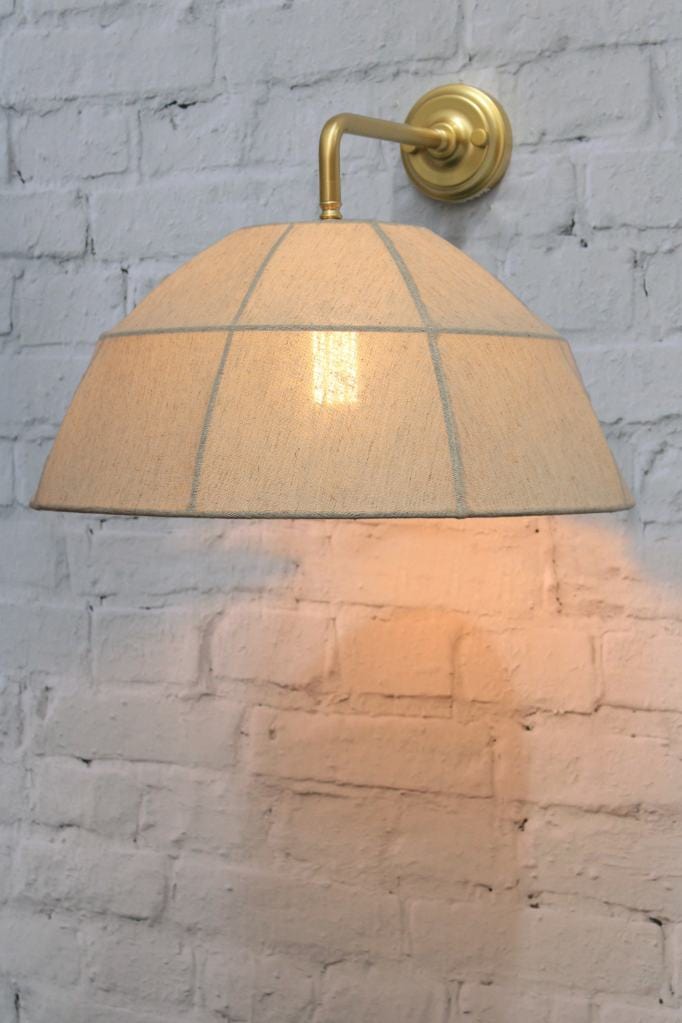 Gold/brass wall light with natural linen shade