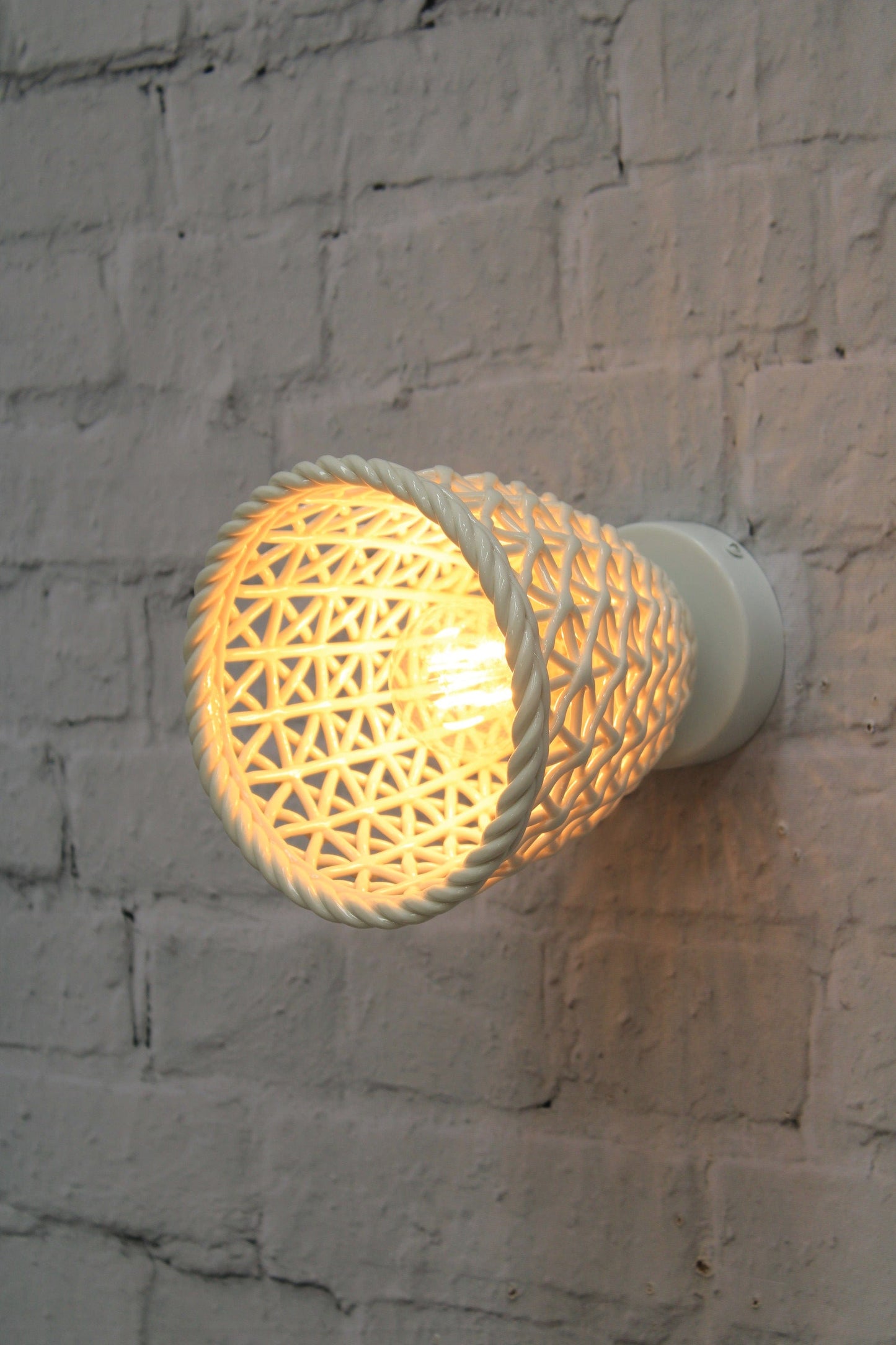 Tall ceramic shade mounted onto brick wall. 