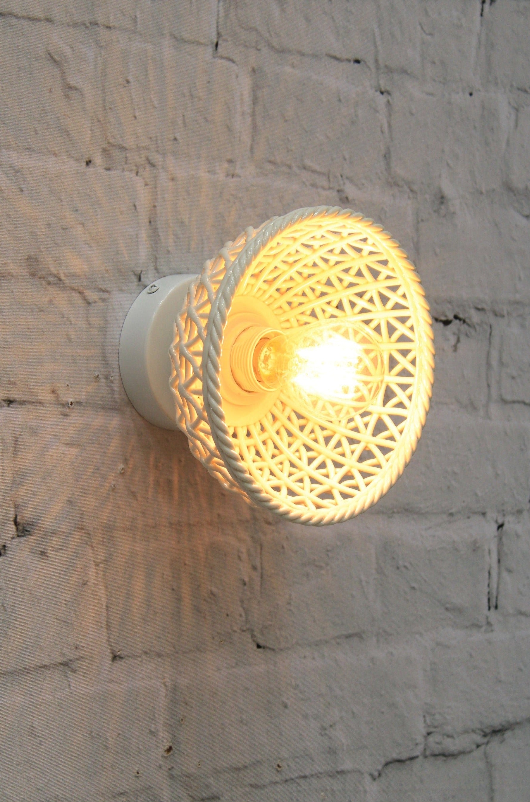 Short ceramic shade mounted onto brick wall. 