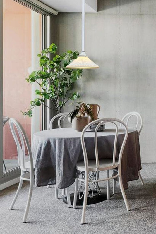 Pole pendant with ceramic shade suspended over dining table