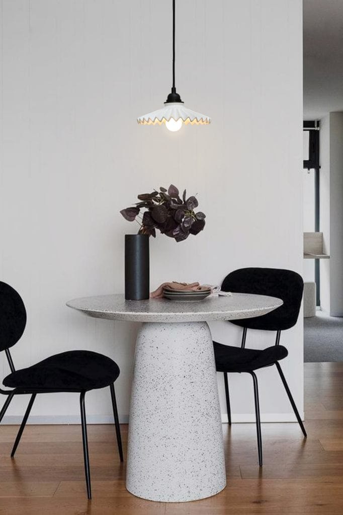 Charmont ceramic pendant light with black cord suspended over table and chairs