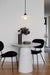 Charmont ceramic pendant light with black cord suspended over table and chairs