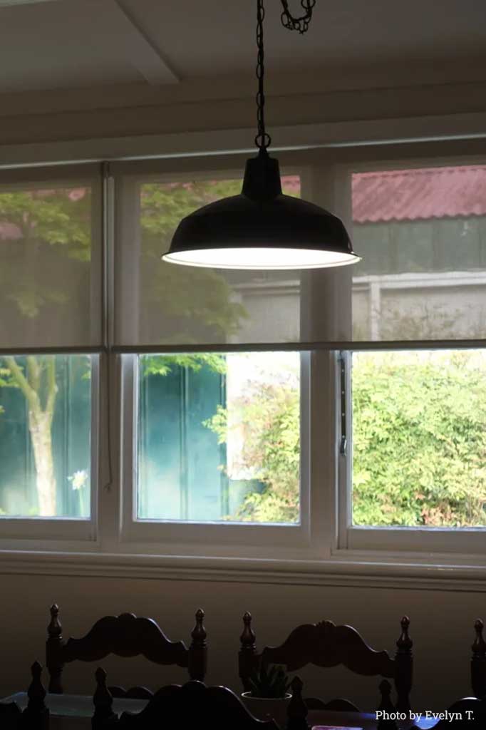 Industrial light with Black Shade over a dining table.