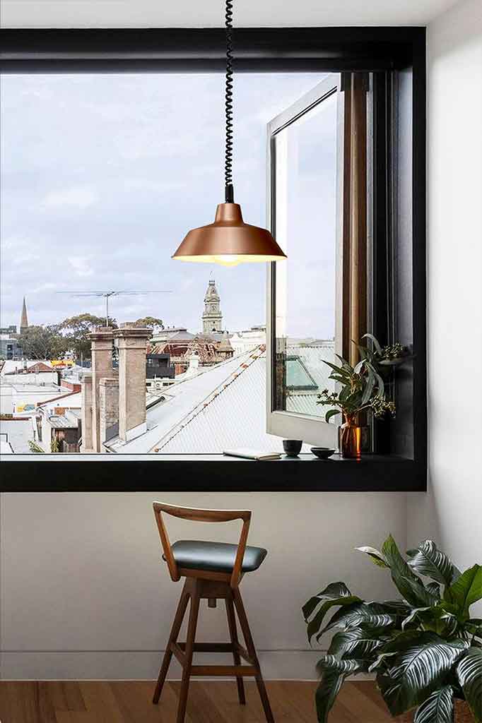 Bright copper rise and fall pendant over a chair.