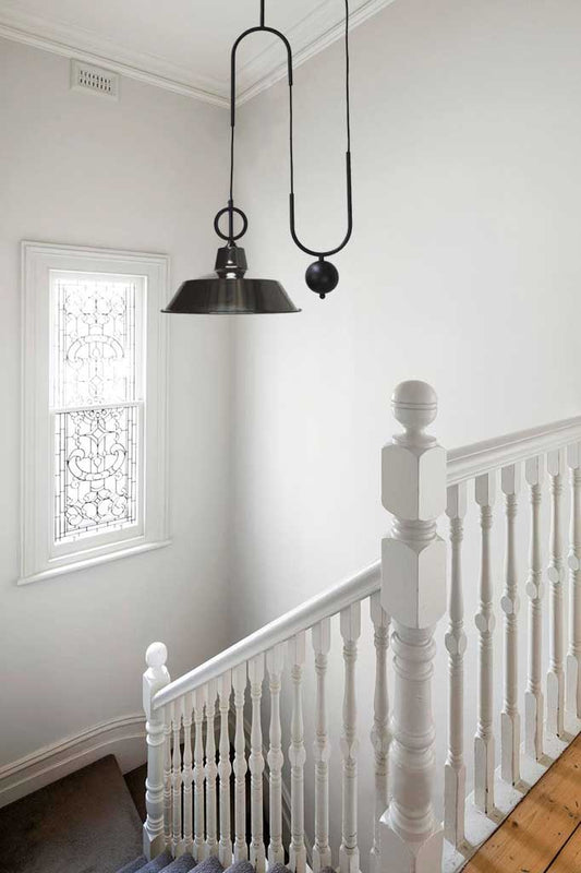 Black factory pulley pendant over stairs.