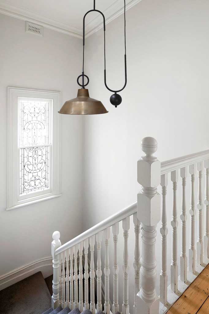 Aged brass factory with black pulley over stairs.