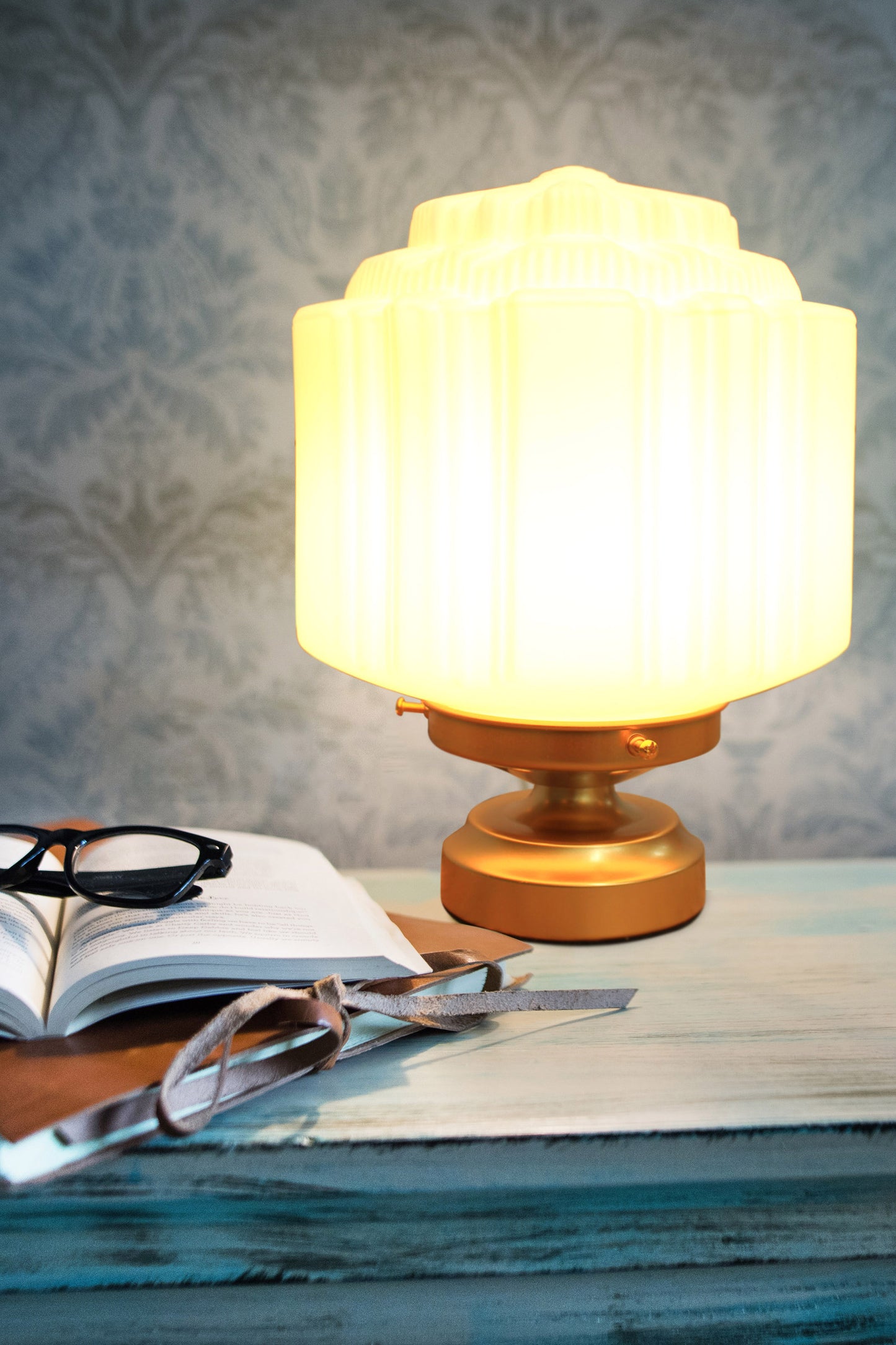 Deco glass lamp with gold base on table