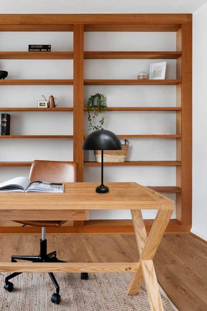 Dome candlestick table lamp in black with a black base placed on a desk within a home office setting. 