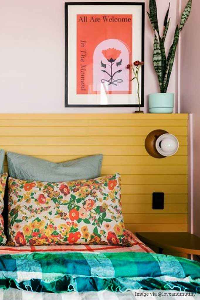 Wood base wall light with bakelite bowl shade in white over a bedside table.