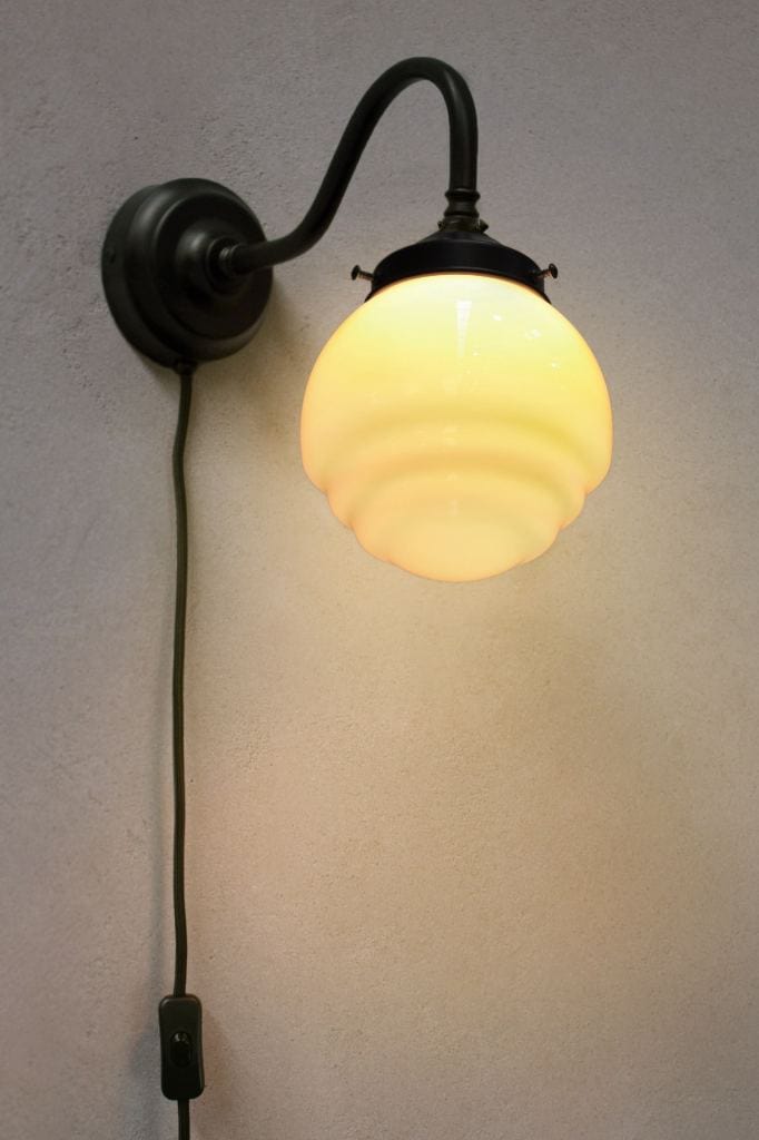 Black wall light with rippled opal shade and wall plug