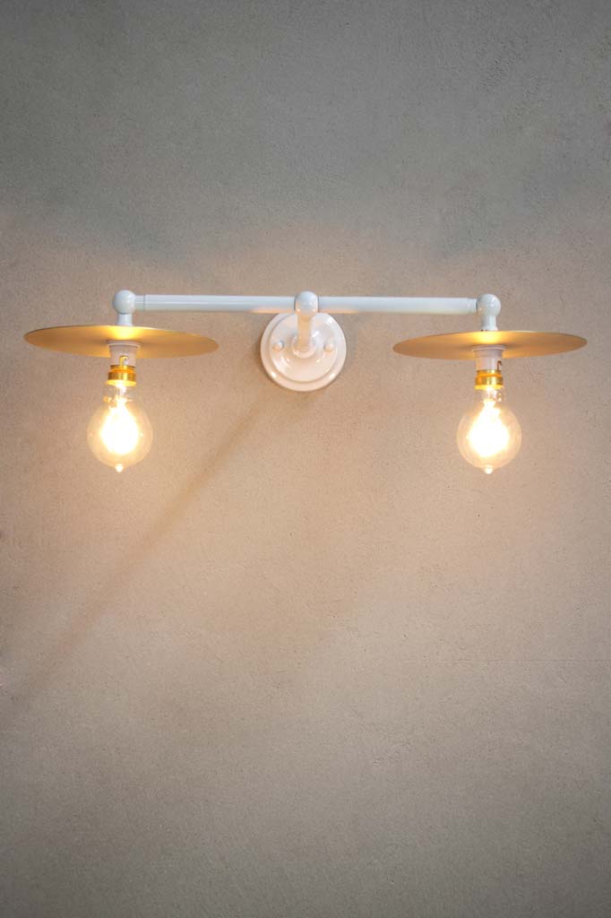 White double arm wall light with small brass discs