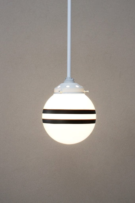 Hand painted opal glass ball pendant light with two stripes hung from white steel pole. 