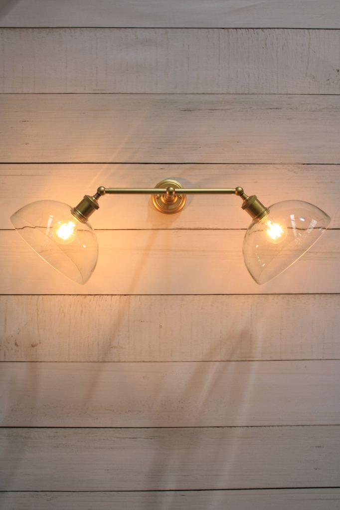 Gold steel double arm wall sconce with clear dome shades