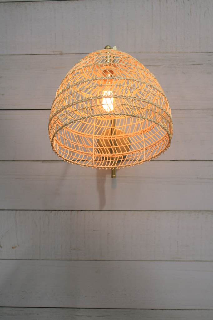 gold/brass wall light with woven rattan shade