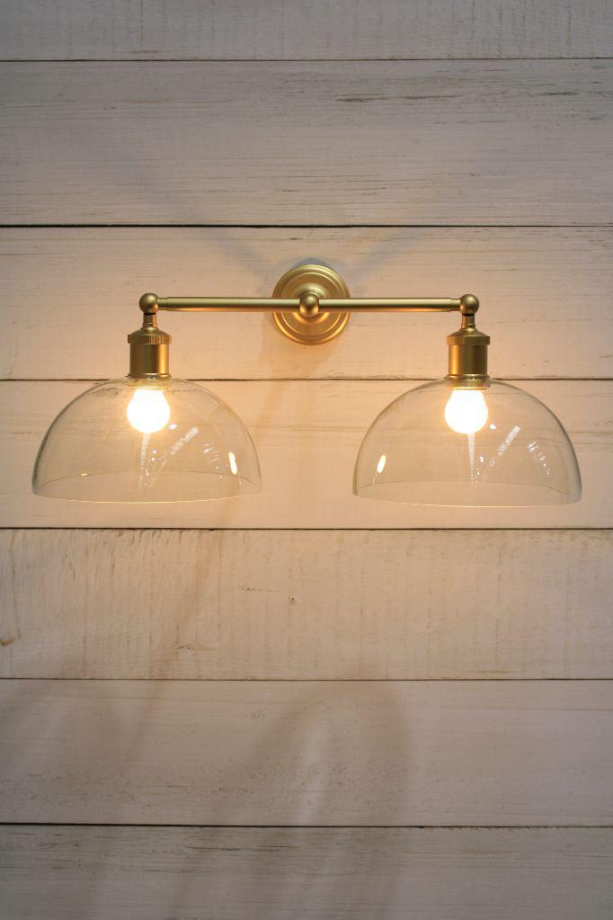 Gold steel double arm wall sconce with clear dome shades