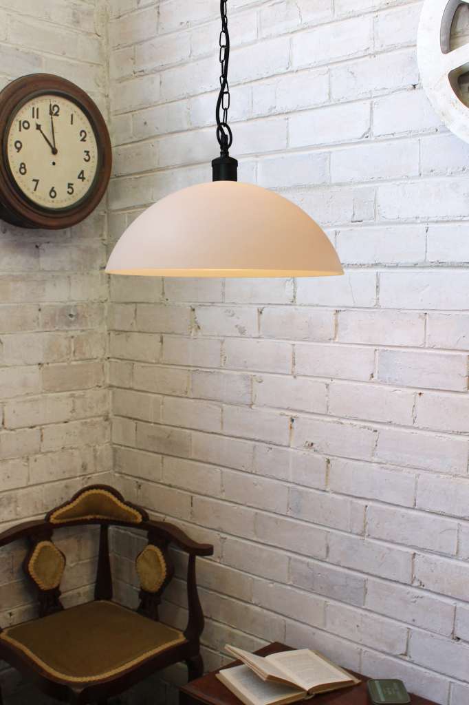 Large opal glass pendant with black chain against a white brick wall