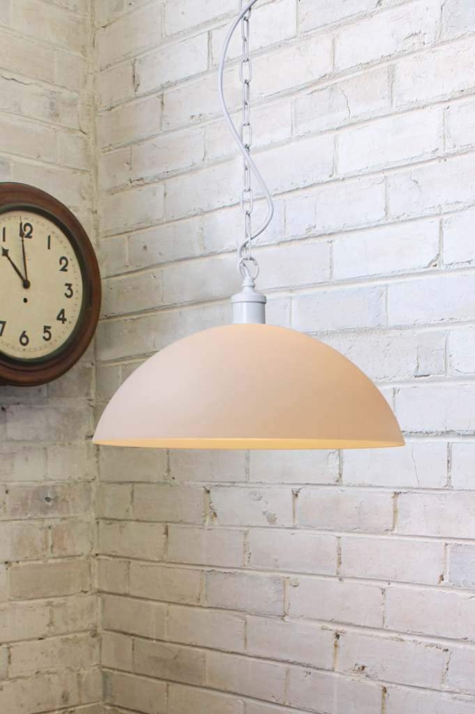 Large opal glass pendant with white chain against a white brick wall