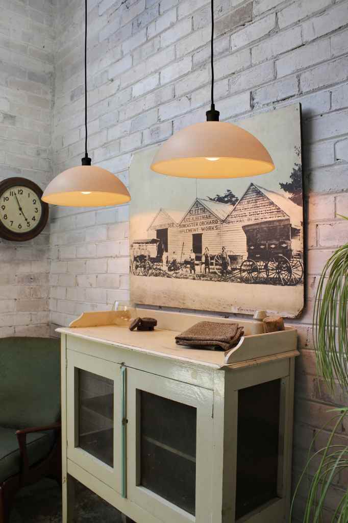 Two opal glass pendant lights suspended next to a white brick wall