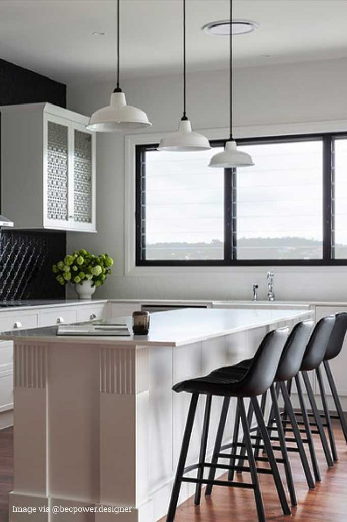 3 warehouse lights in white over a kitchen island.