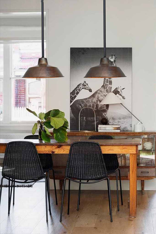 Black pole pendant with copper shade over dining table.