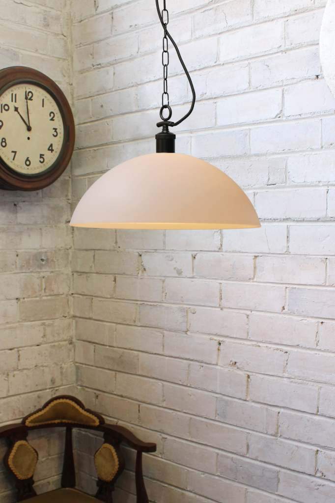 Large opal glass pendant with black chain against a white brick wall